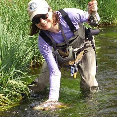 female flyfisher in the water with their catch
