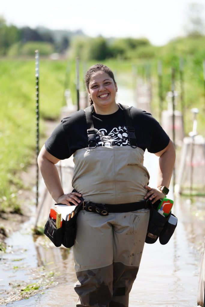 female conservation worker standing in stream smiling